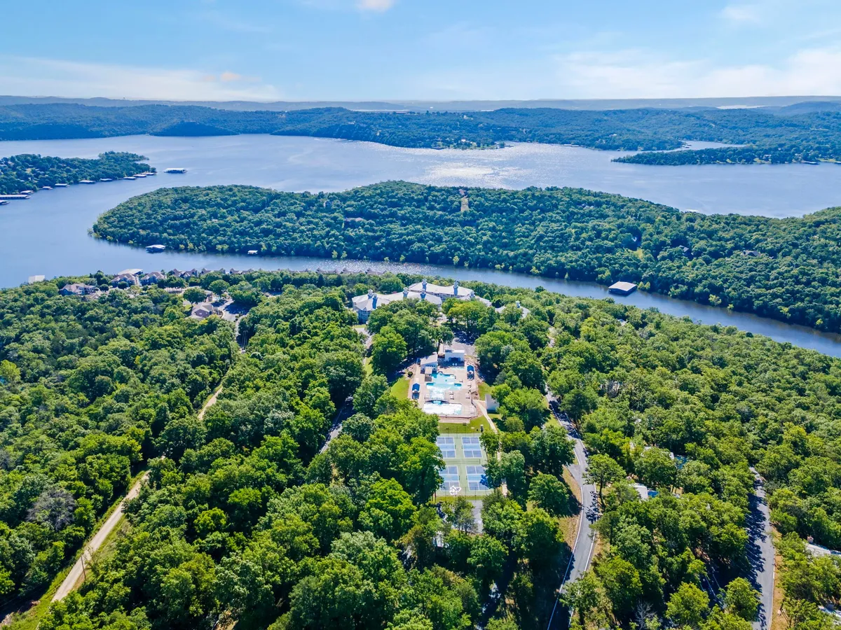 A broad, tranquil view encompassing Table Rock Lake, lush greenery, a sparkling swimming pool, and tennis courts. The image hints at a wide range of recreational opportunities, from boating and swimming to playing tennis and hiking, all set against a backdrop of natural beauty and open skies.