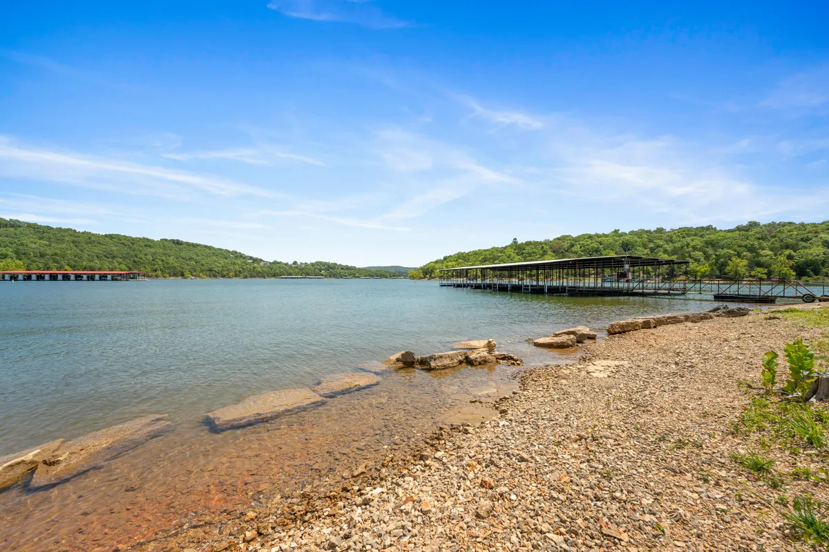 A tranquil lake scene with a dock and a rocky shoreline. The inviting water and open shoreline suggest spots where dogs can splash and play, while the dock hints at opportunities for lakeside adventures. The natural landscape conveys a sense of relaxation and exploration.