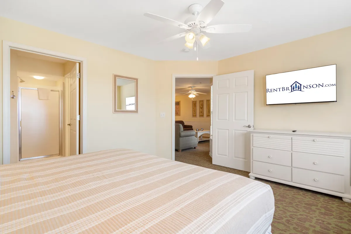 A comfortable king bedroom with a stylish bed, soft linens, a television, a dresser, and a mirror. The room feels both restful and inviting, providing the perfect space for unwinding after a day of activities.