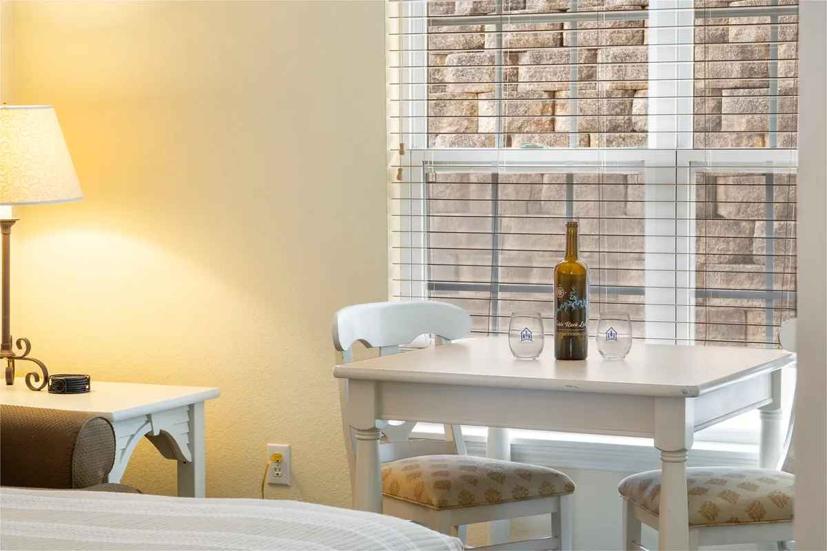 This cozy interior shot shows a white table set for two, complete with a wine bottle and two glasses. The scene feels intimate and inviting, evoking the idea of sharing a quiet drink together in the comfort of your retreat.
